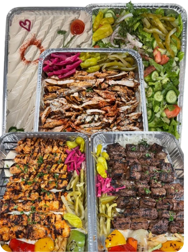 Catering trays of hummus, chicken shawarma, salad, and chicken and beef kabobs